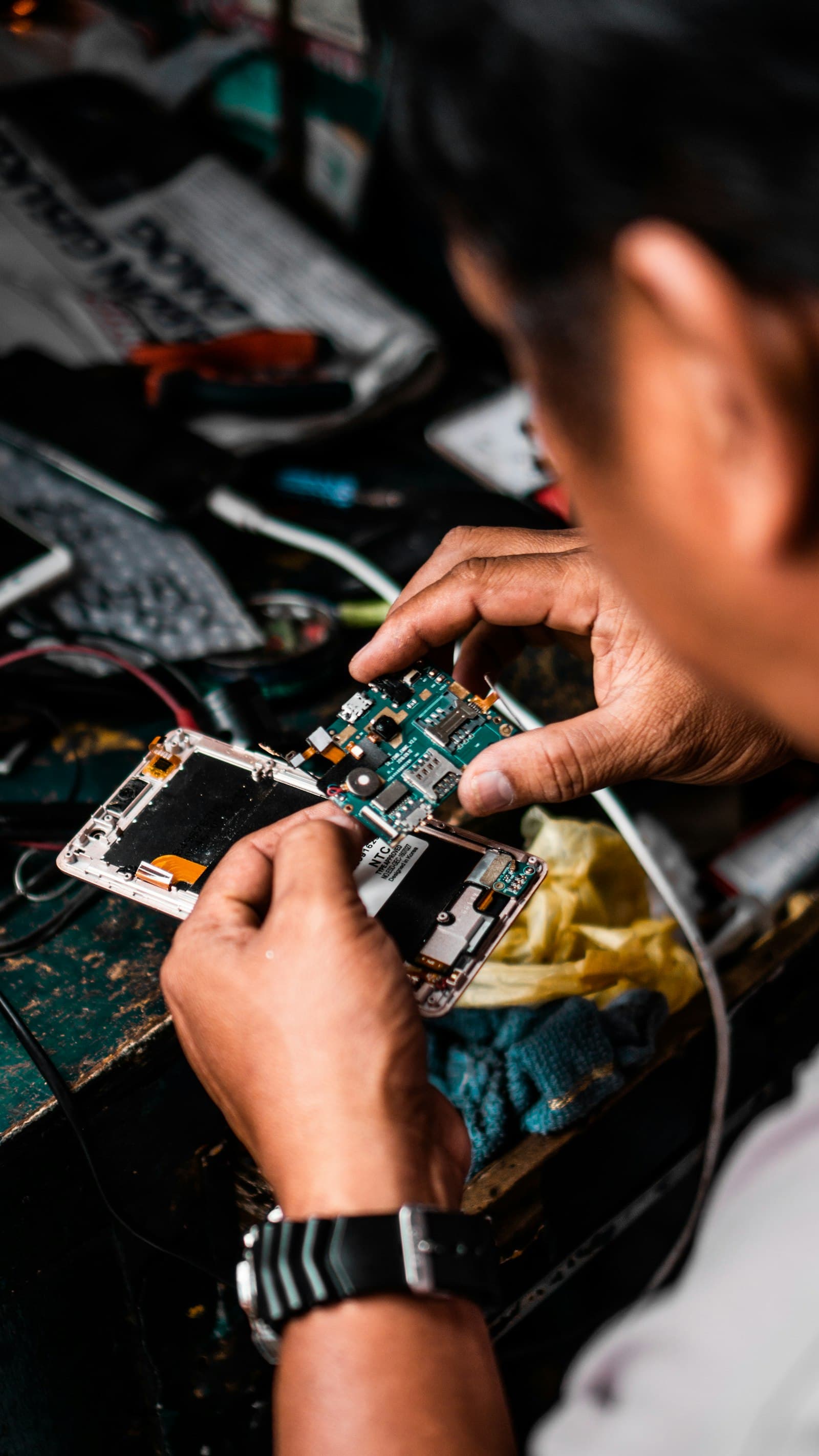 Technician examining a smartphone mainboard