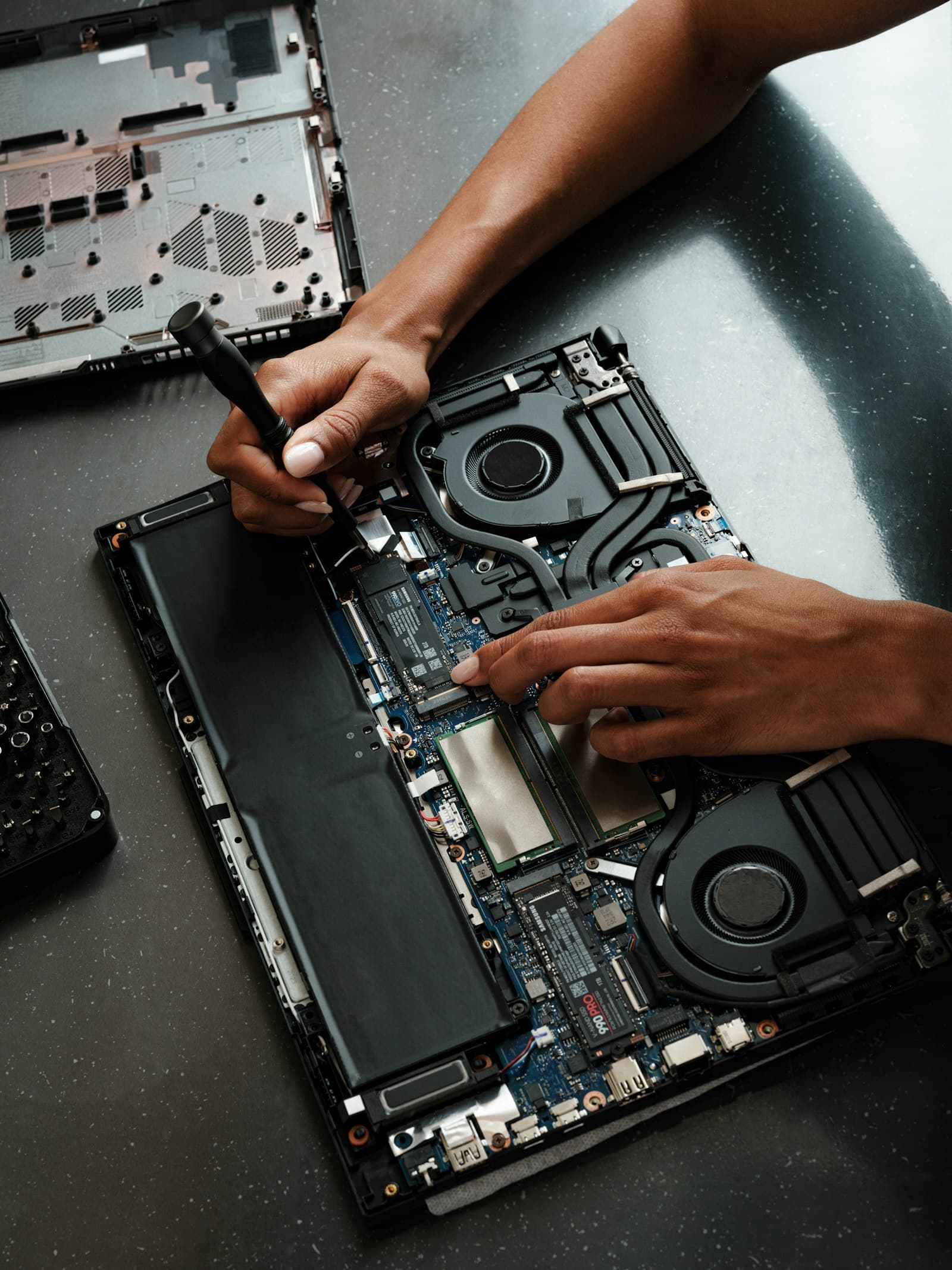 Hands using a screwdriver inside an opened laptop