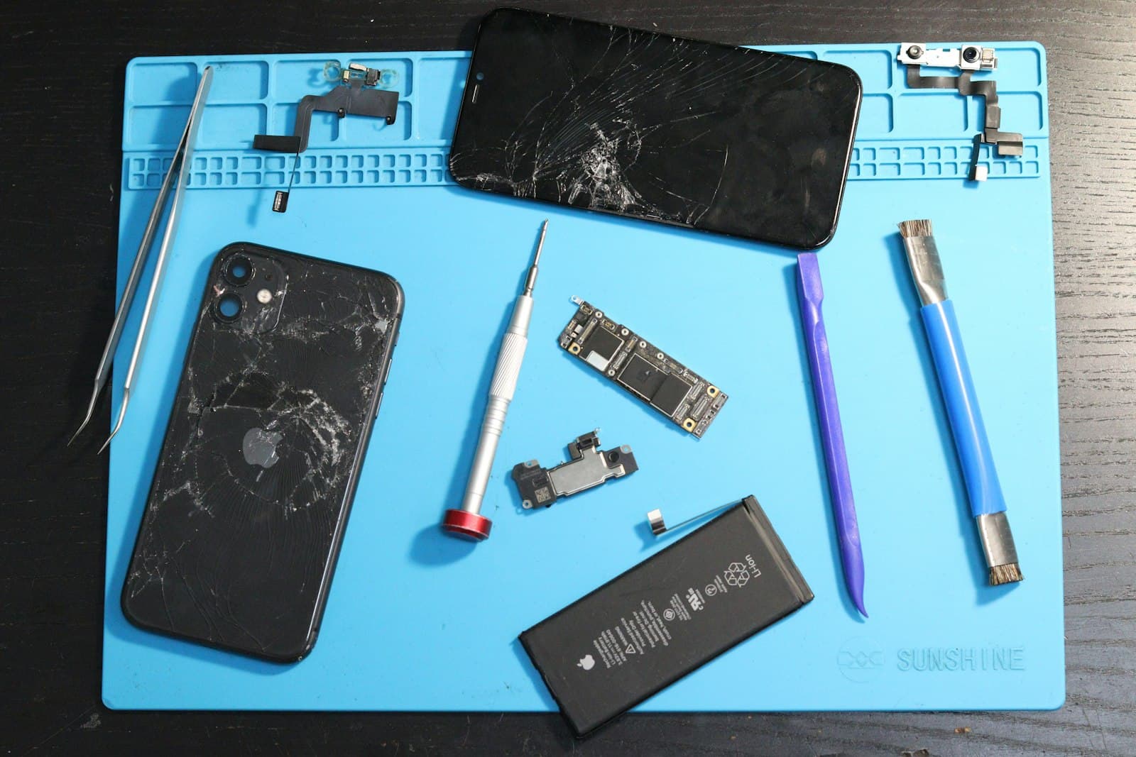 Disassembled smartphone and repair tools on an anti-static mat