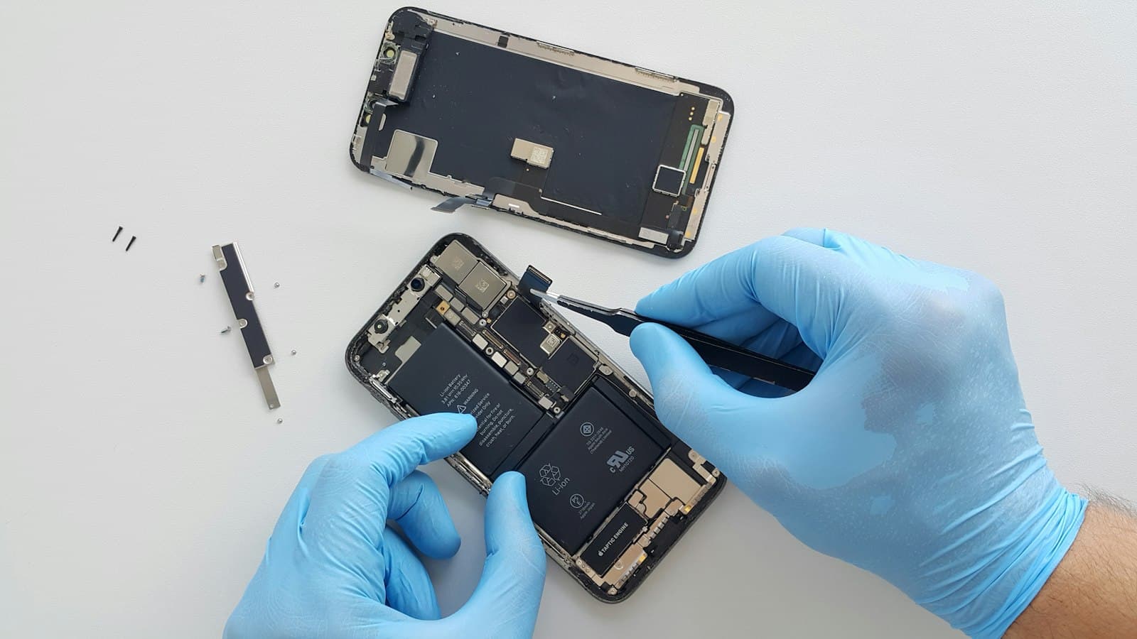 Gloved technician working inside an opened smartphone